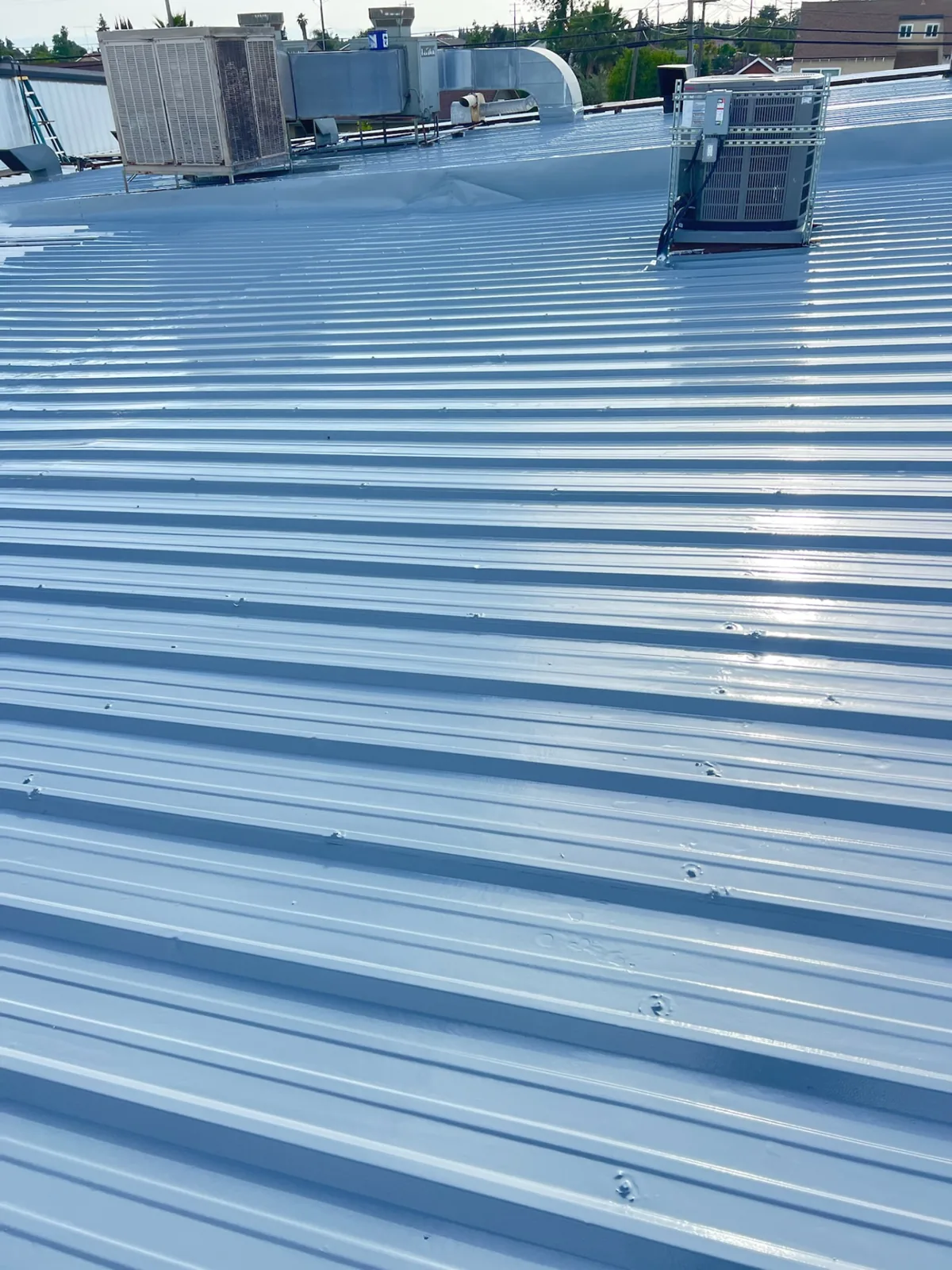 Coated commercial metal roof with rooftop HVAC units.